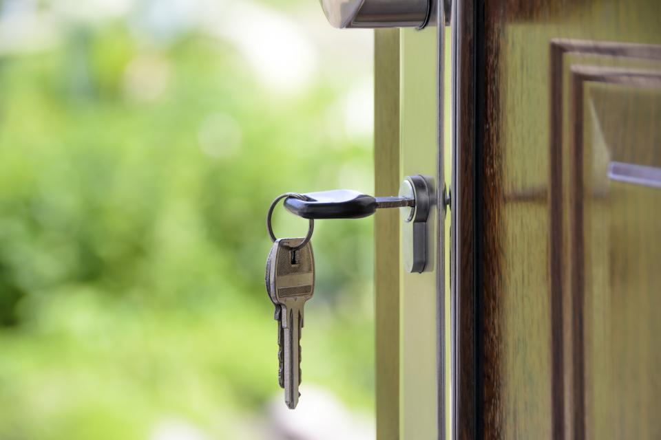 A set of house keys hanging in the lock of a front door